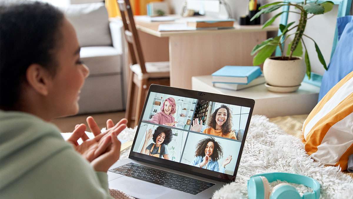 Young person at a laptop. There are four other young people on the screen in an online meeting.