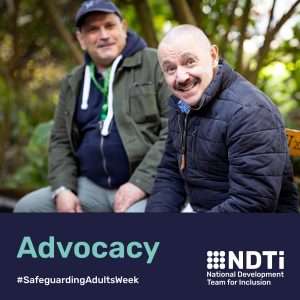 Two males are sitting outside on a bench. They are both looking towards the camera and smiling. One is wearing a sunflower hidden disability lanyard. Beneath is the word advocacy.