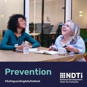 Two people are sat at at a table smiling and chatting. They both have notebooks and a drink. One may be disabled. Beneath is the word prevention.