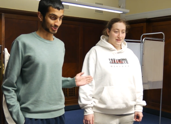 Two people standing together inside a polling station.