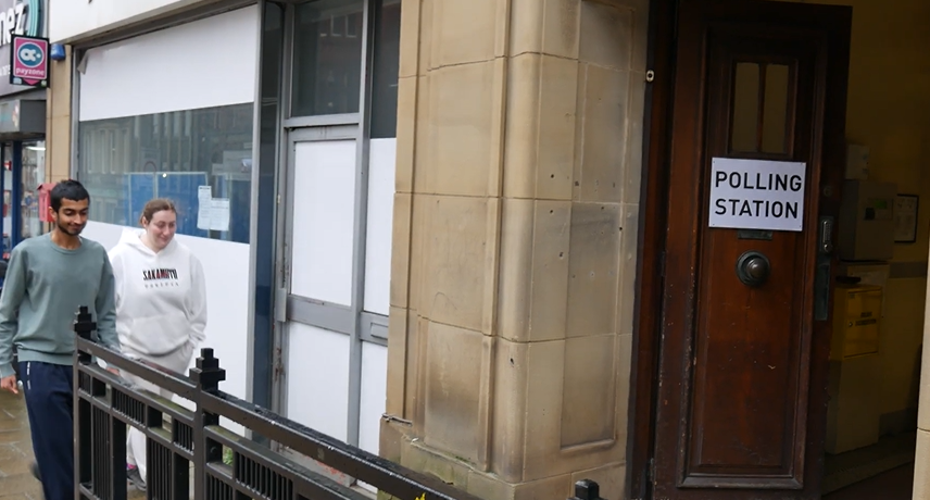 Two people approaching the outer door of the polling station.
