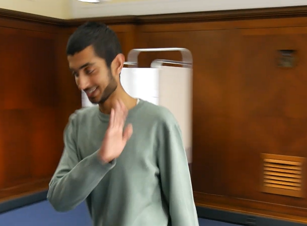 A person in a polling station is waving goodbye as they leave.